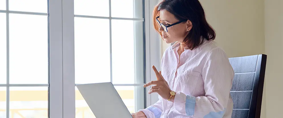 Mujer participando en una consulta médica online sobre atraso menstrual, utilizando una computadora portátil en un entorno hogareño.