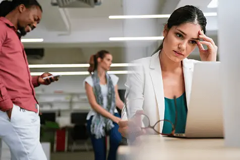 Mujer estresada en el trabajo preocupada por atraso menstrual sin encontrar solución.